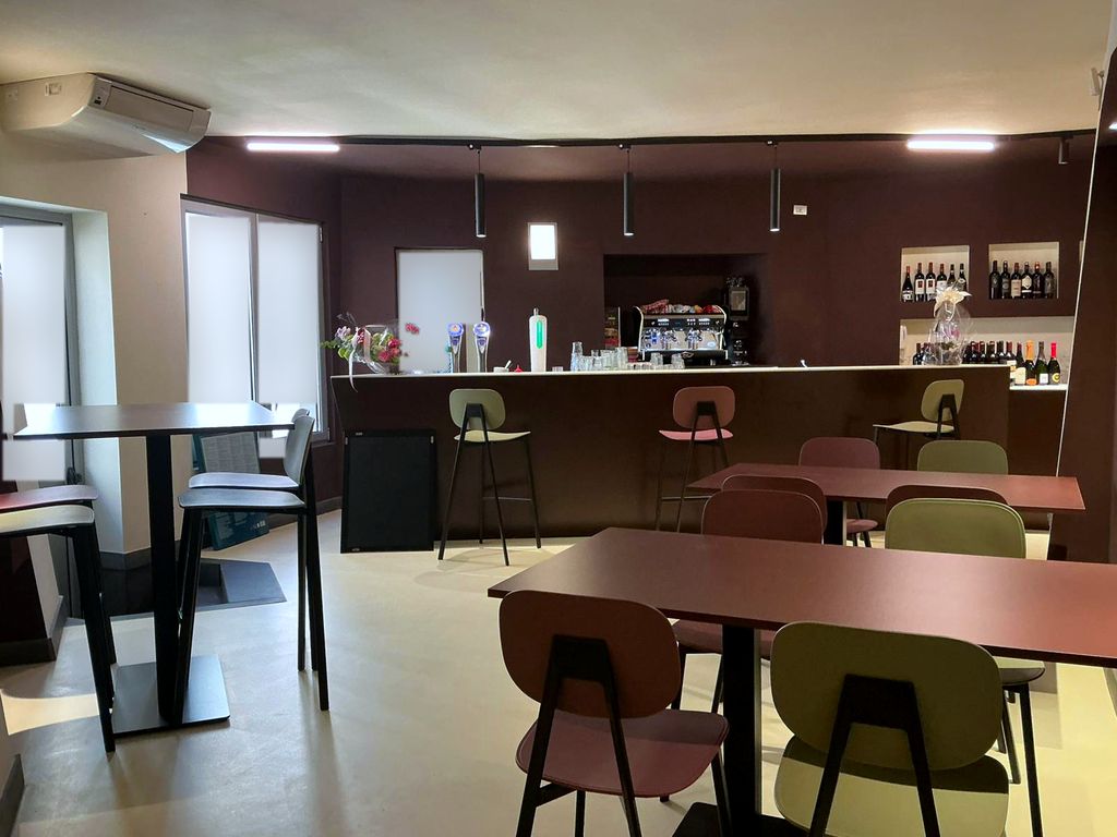 La barra del Regina Ristopub, con taburetes y mesas rosa y verde salvia