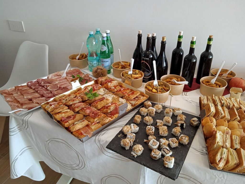 Una mesa con embutidos, focaccias, bocaditos y vino tinto