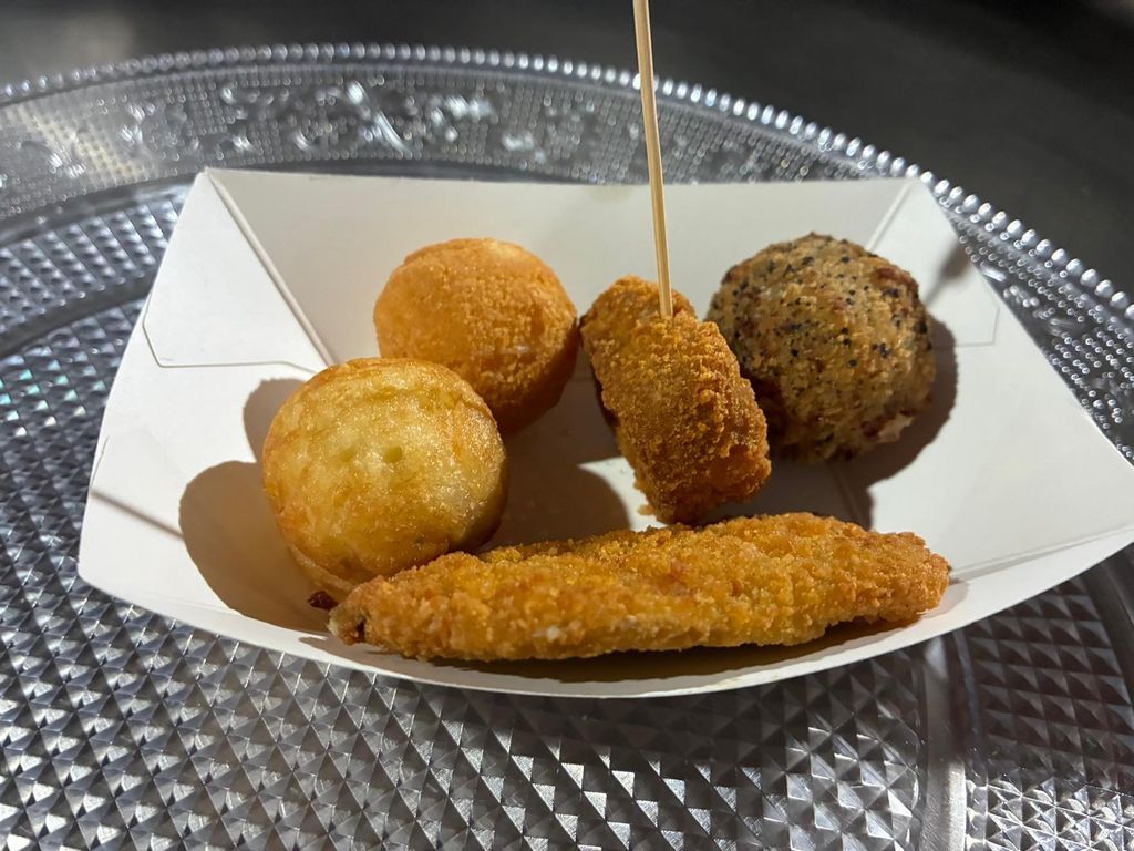 Arancini, croquetas y un filete empanado en una bandejita de papel