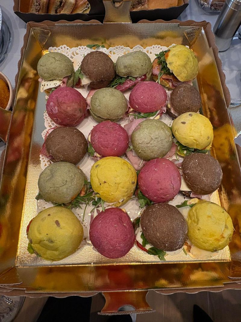 Una bandeja dorada de panecillos tiernos amarillos, rosas, verdes y de cacao