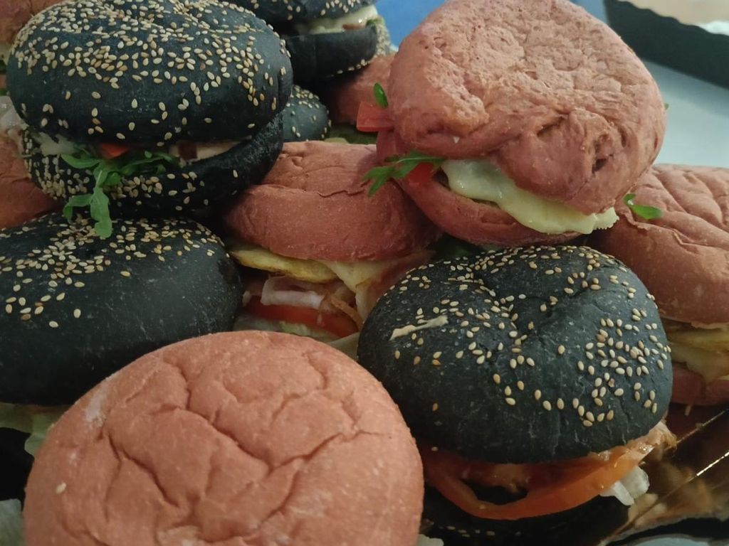 Panecillos negros con sésamo y panecillos rosas rellenos de tomate y queso