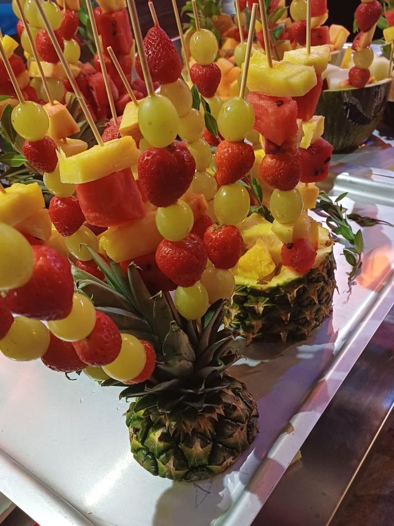 Brochetas de fresas, uva, piña y sandía clavadas en una piña