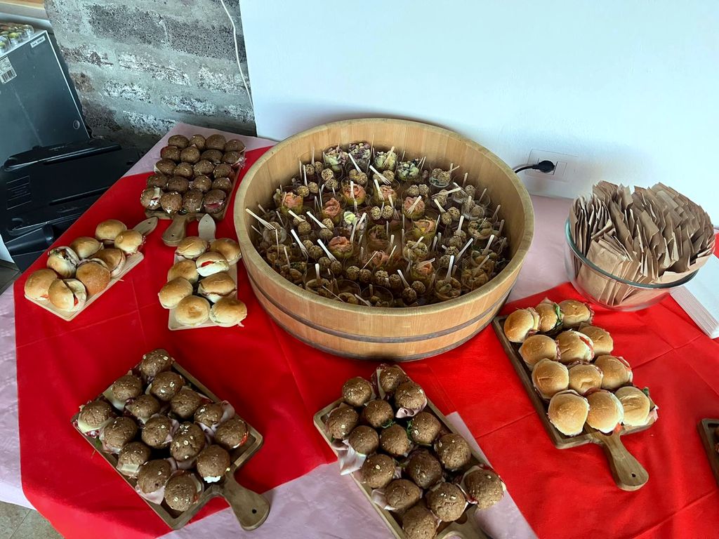 Una tina de madera llena de brochetas entre bandejas de bocadillos