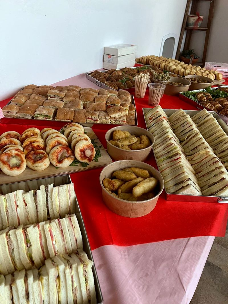 Bandejas de tramezzini, minipizzas y cuencos de fritos sobre un mantel rojo