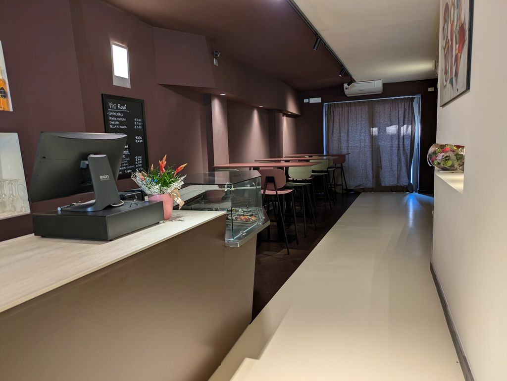 El pasillo con la barra a la izquierda y las mesas altas hacia las cortinas del fondo