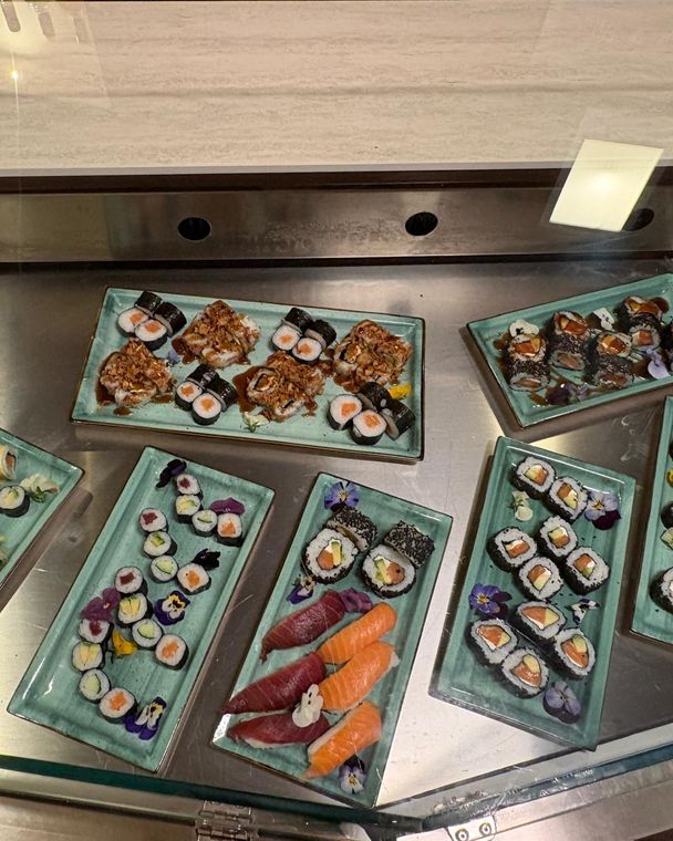 Bandejas de sushi, nigiri y uramaki en la vitrina de la barra