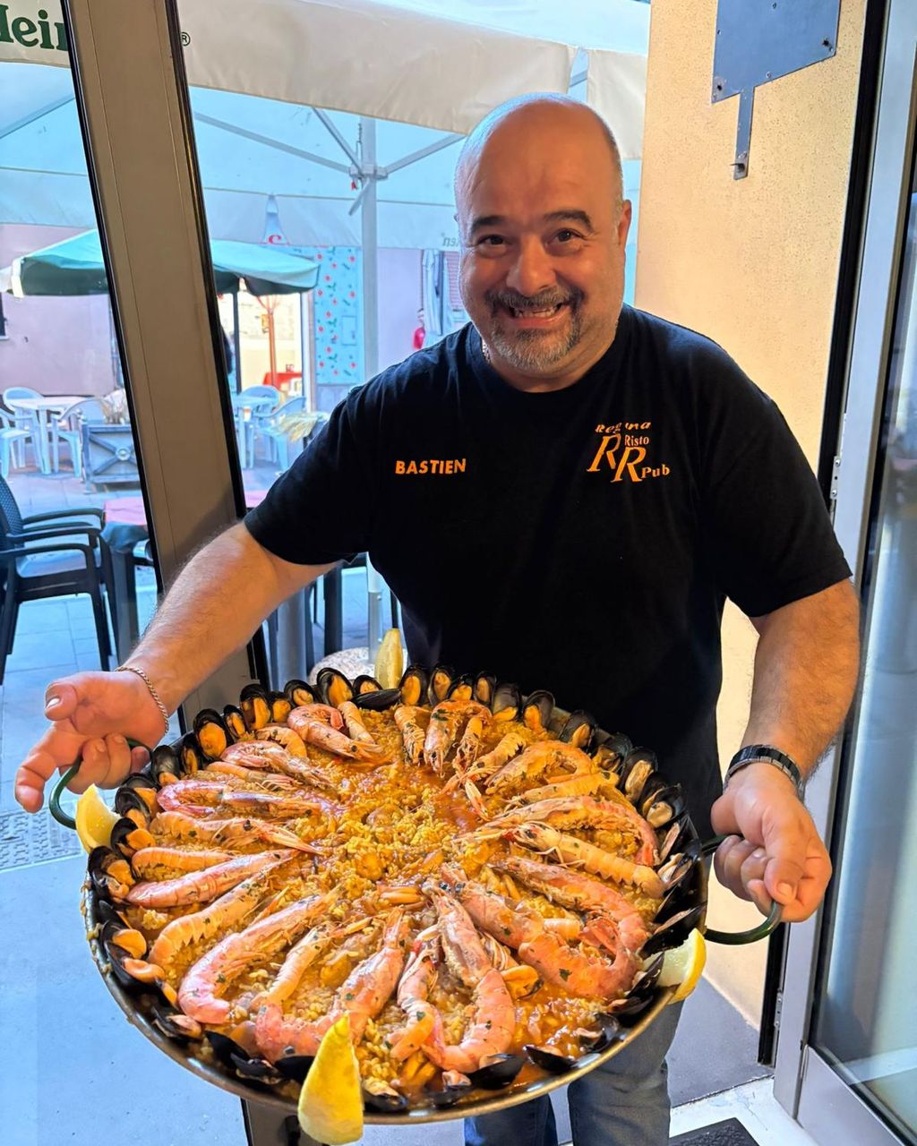 Bastien en la puerta del local con una gran paella de marisco