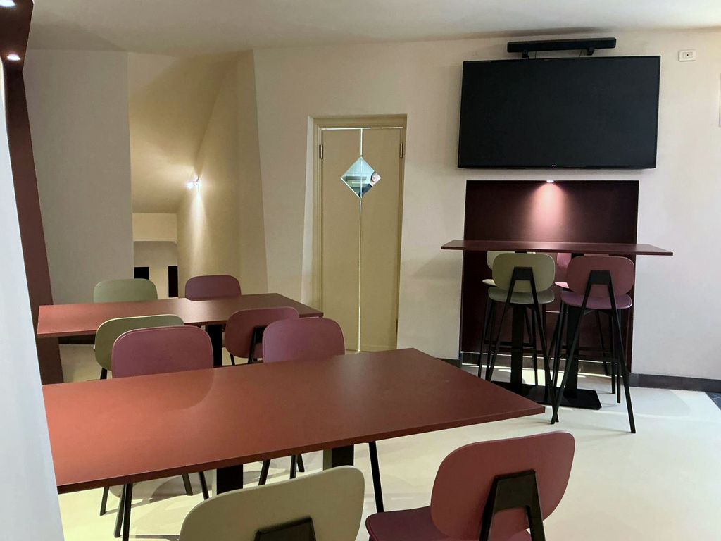 La sala con las mesas largas y la pantalla
